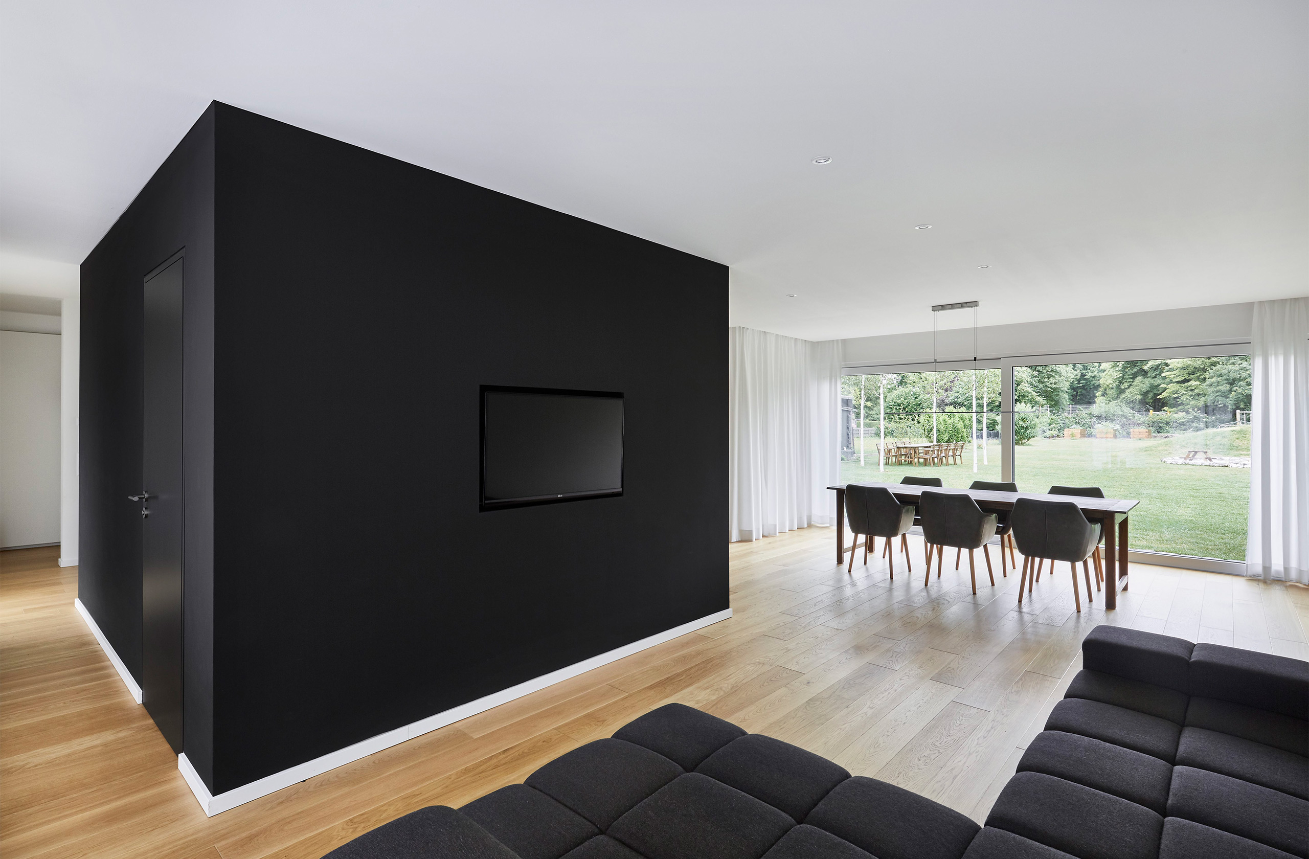 Wohnbereich mit schwarzer Wand, heller Eichenboden und Ausblick in den Garten