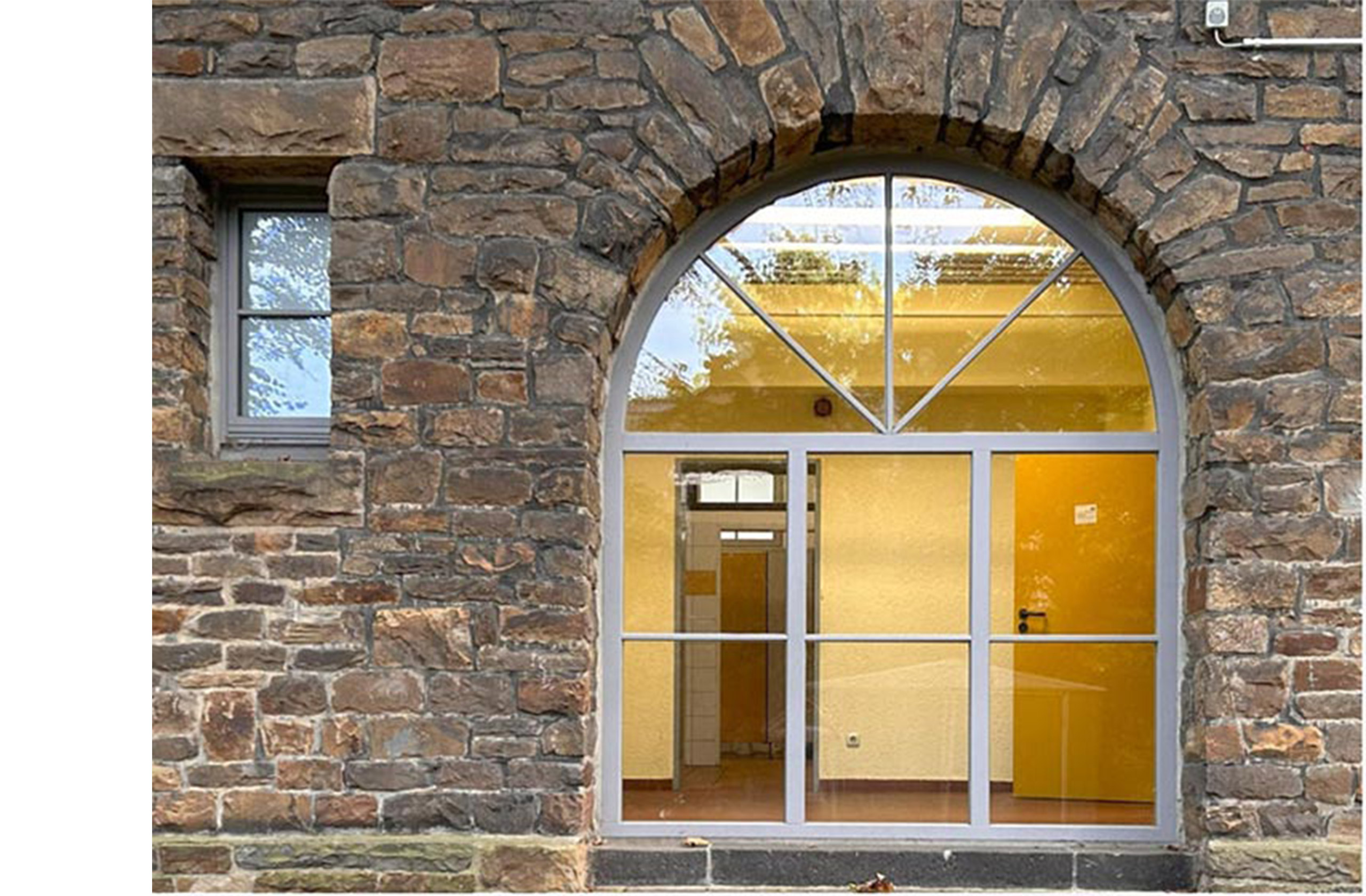 Eingangsbereich der GGS Hölterschule mit Rundbogen und Natursteinfassade