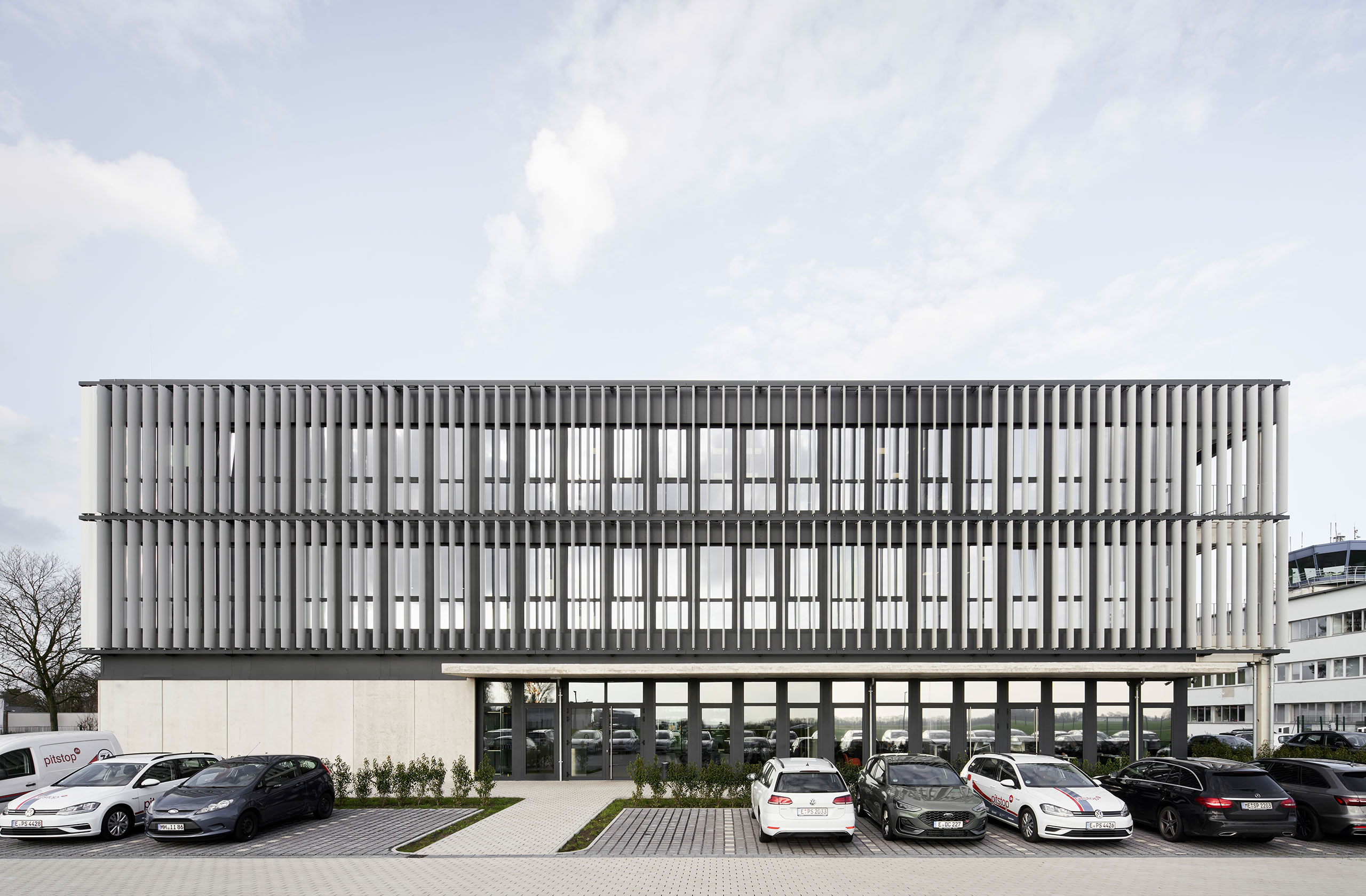 Gesamtansicht der Hauptverwaltung pitstop am Tag mit Parkplatz im Vordergrund