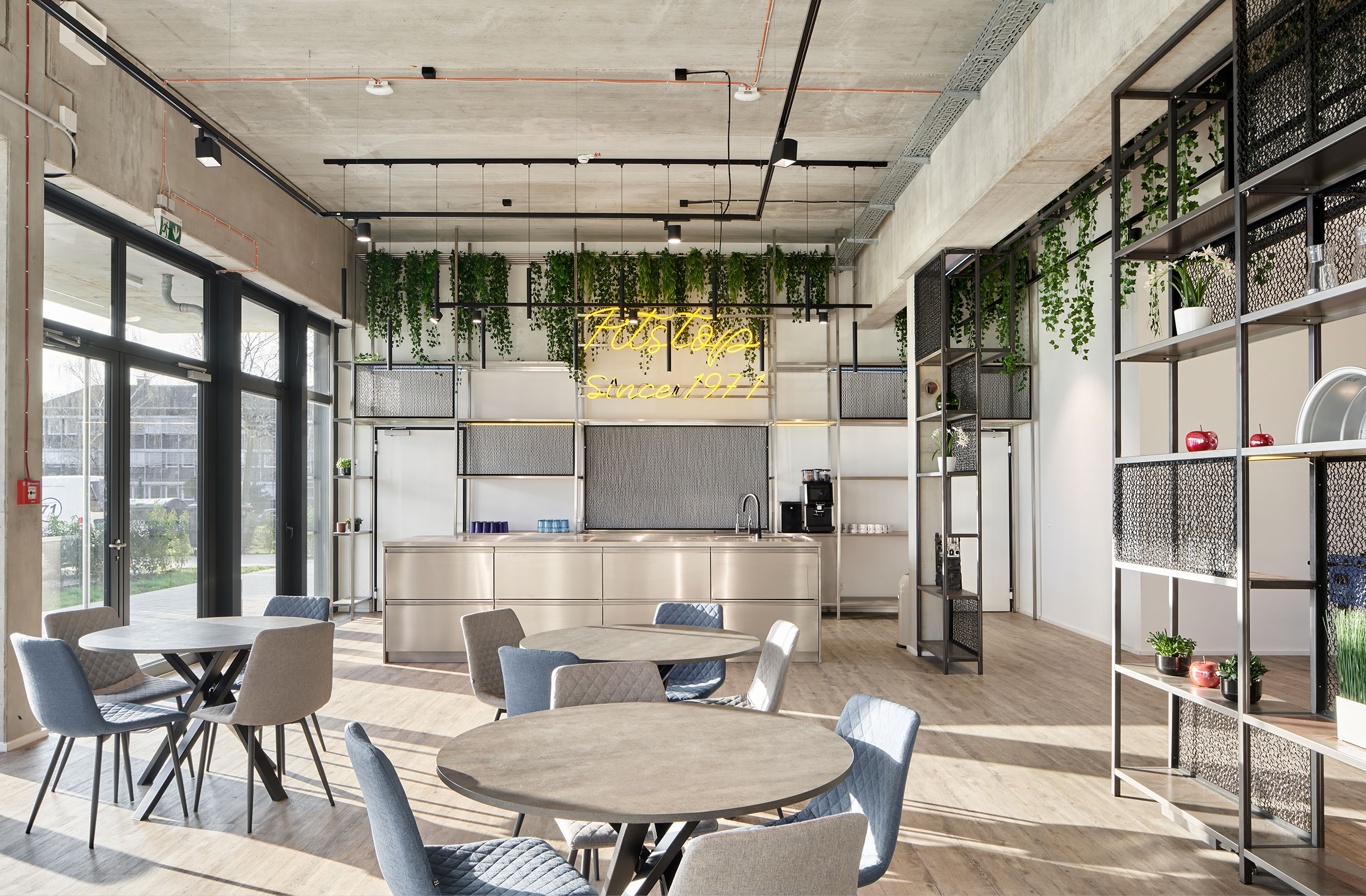 Innenraum mit offenem Aufenthaltsbereich, industriellem Stil und Begrünung
