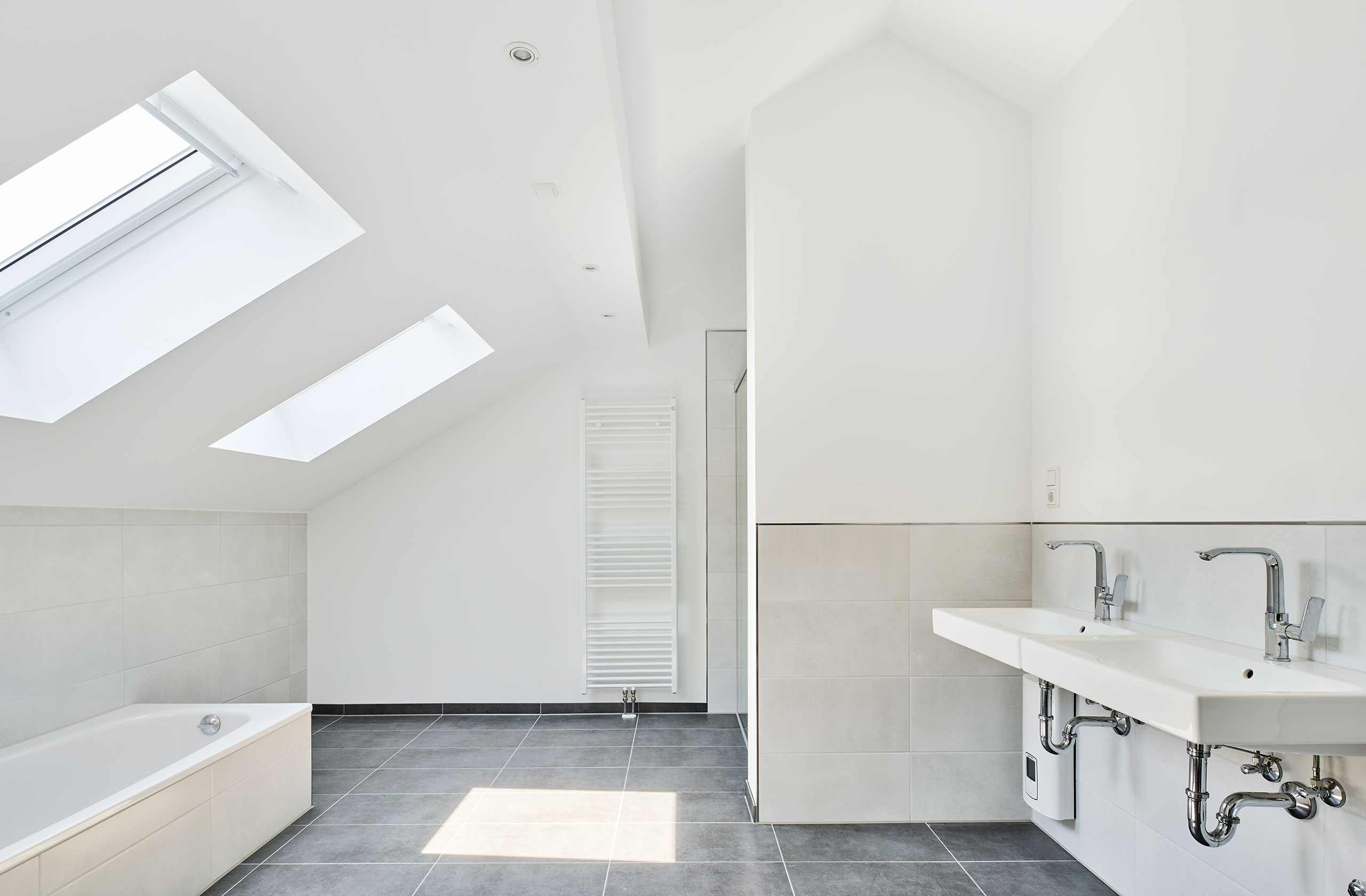 Helles Badezimmer mit Dachfenster, Wanne und großformatigen Fliesen
