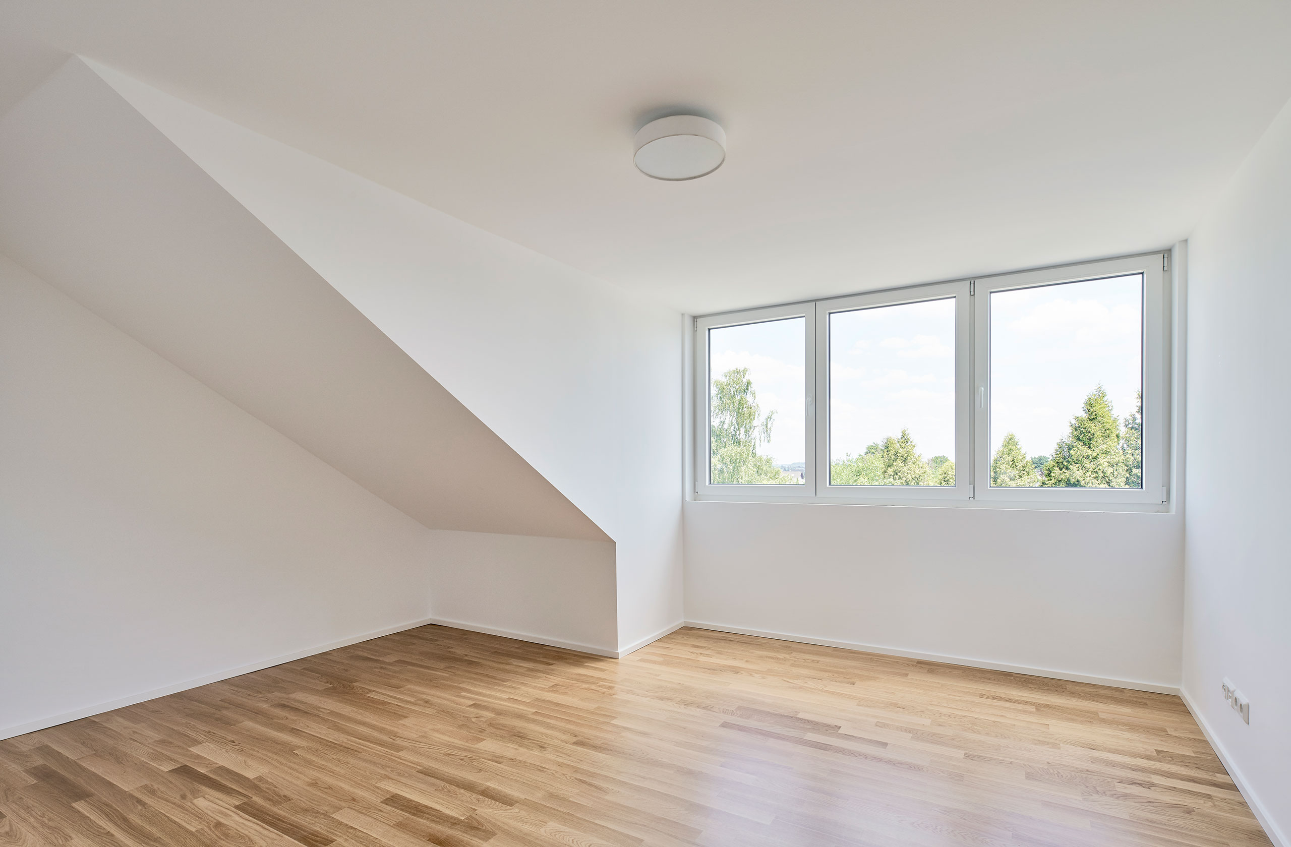 Wohnraum im Dachgeschoss mit Holzfußboden und schrägen Wänden