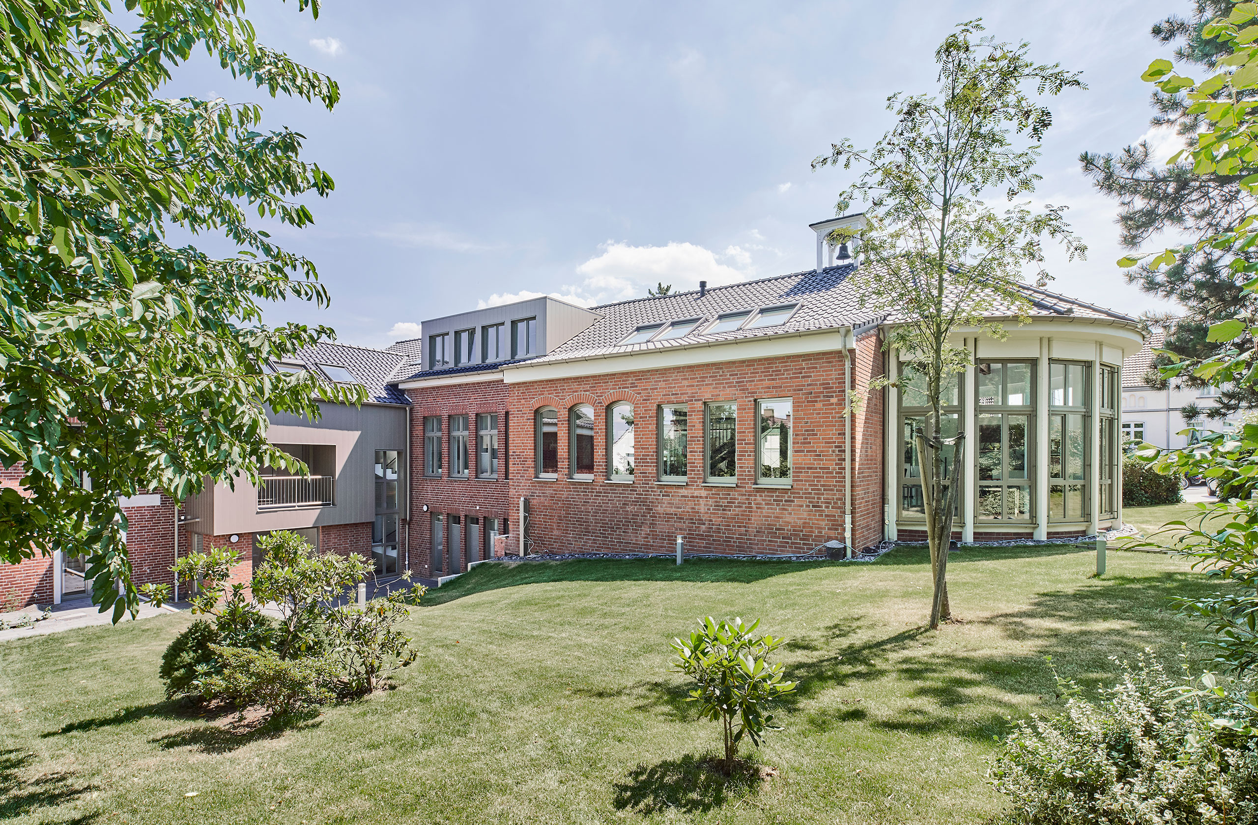 Außenansicht mit Wintergarten und großzügiger Grünfläche