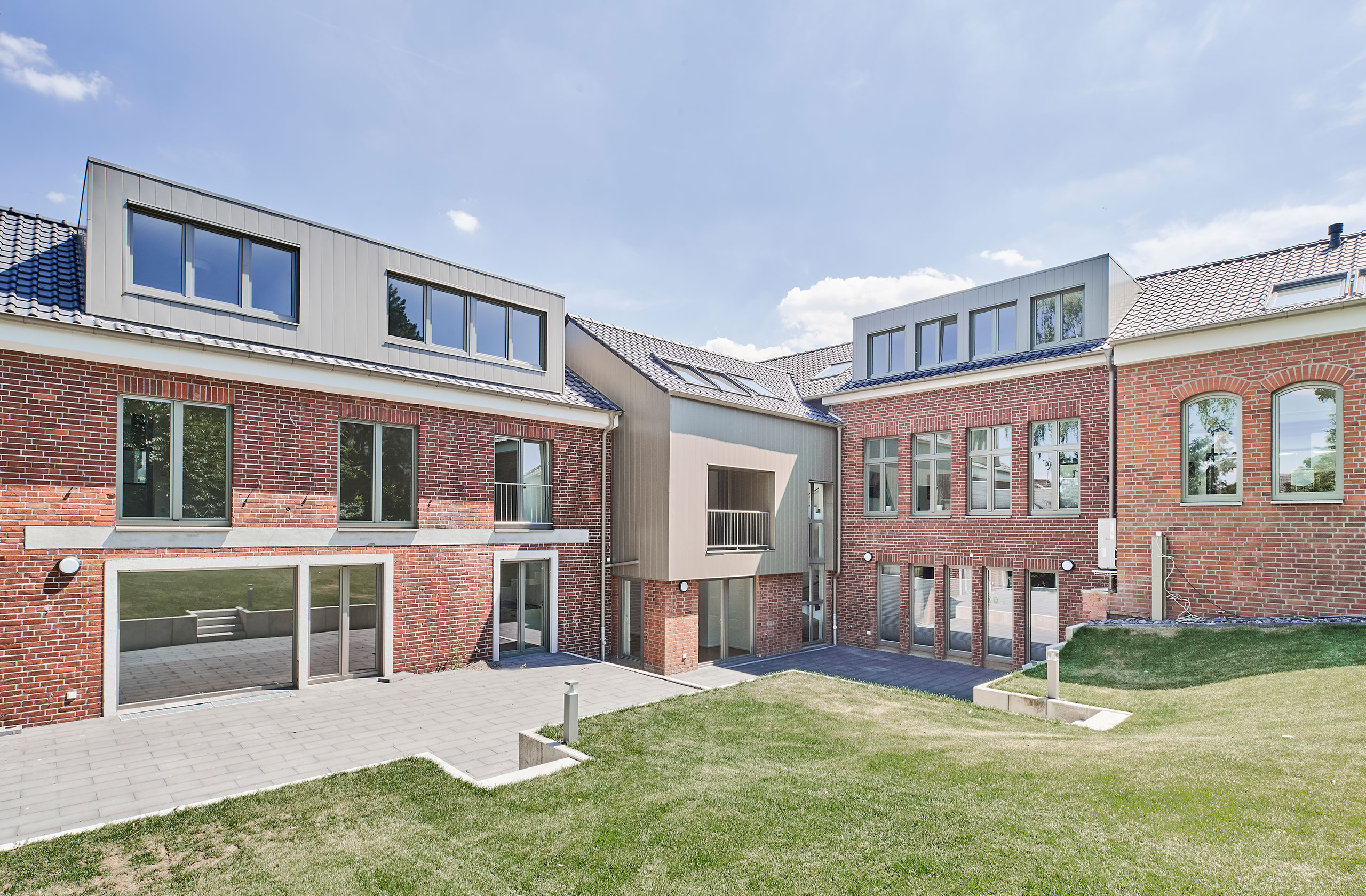 Seitenansicht mit Ziegelmauerwerk und moderner Dachaufstockung