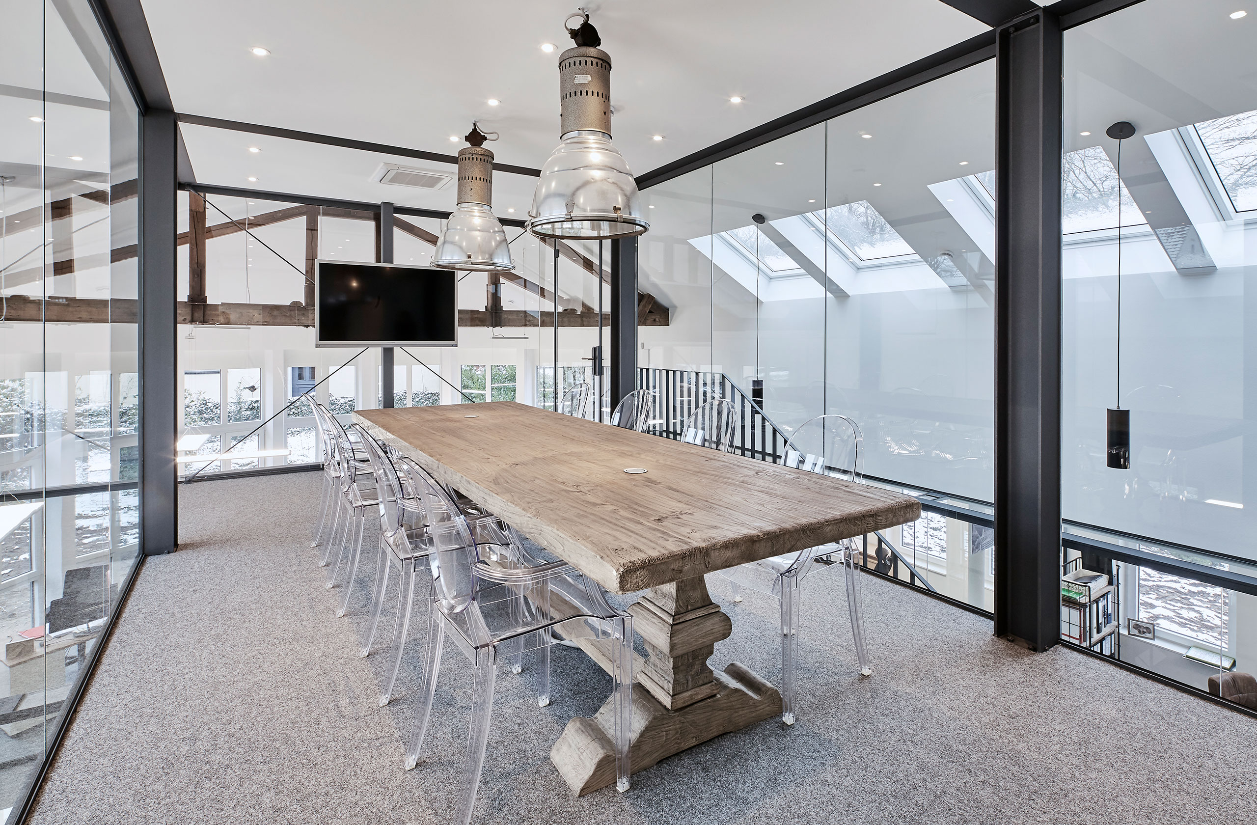 Besprechungsraum mit Glaswänden, Holztisch und Lichteinfall durch Dachfenster