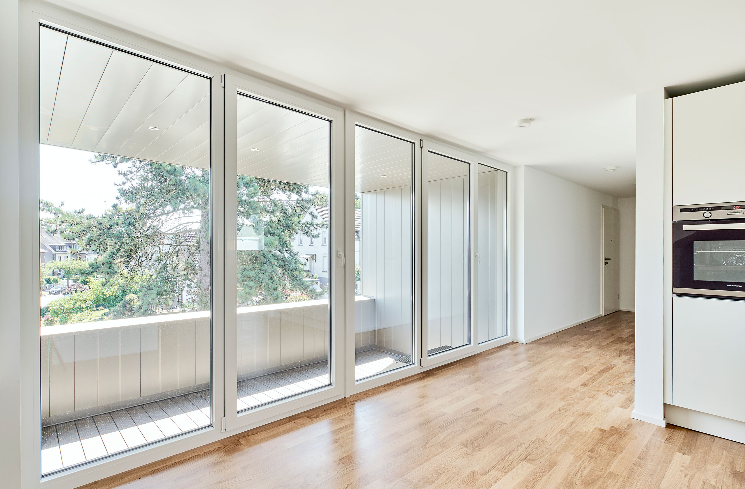 Wohnküche mit bodentiefen Fenstern und Zugang zur Loggia