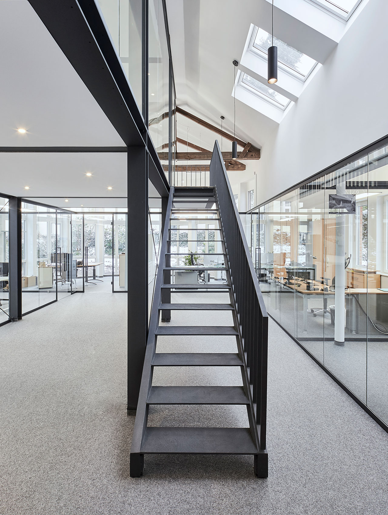 Blick auf die Treppe im offenen Bürobereich mit Stahlrahmen und Glasabtrennungen