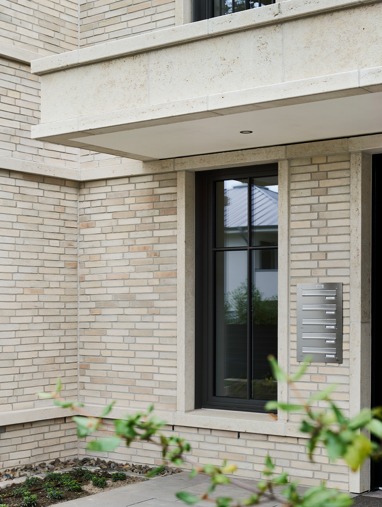 Detailansicht des Eingangsbereichs mit heller Klinkerfassade und Natursteinrahmung