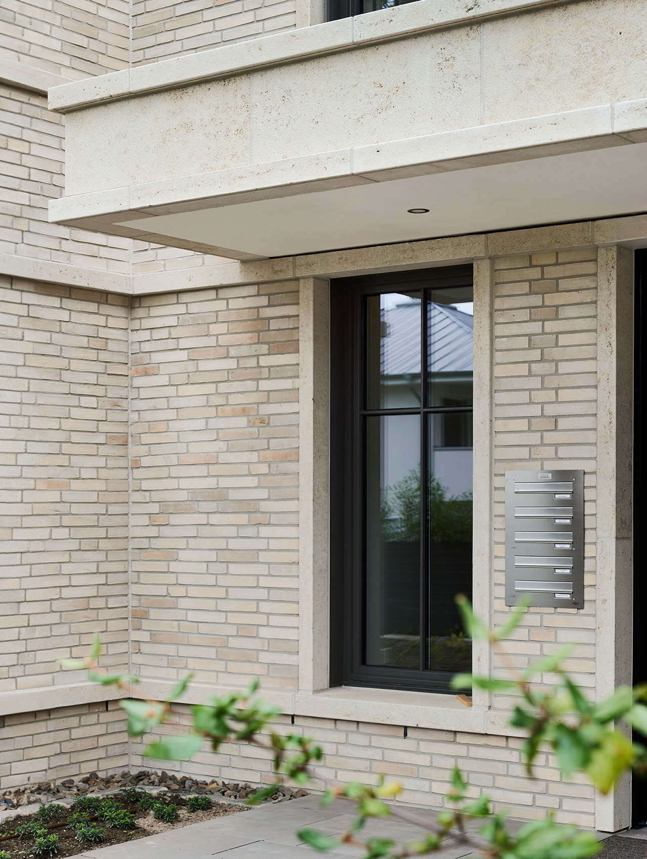 Detailansicht des Eingangsbereichs mit heller Klinkerfassade und Natursteinrahmung