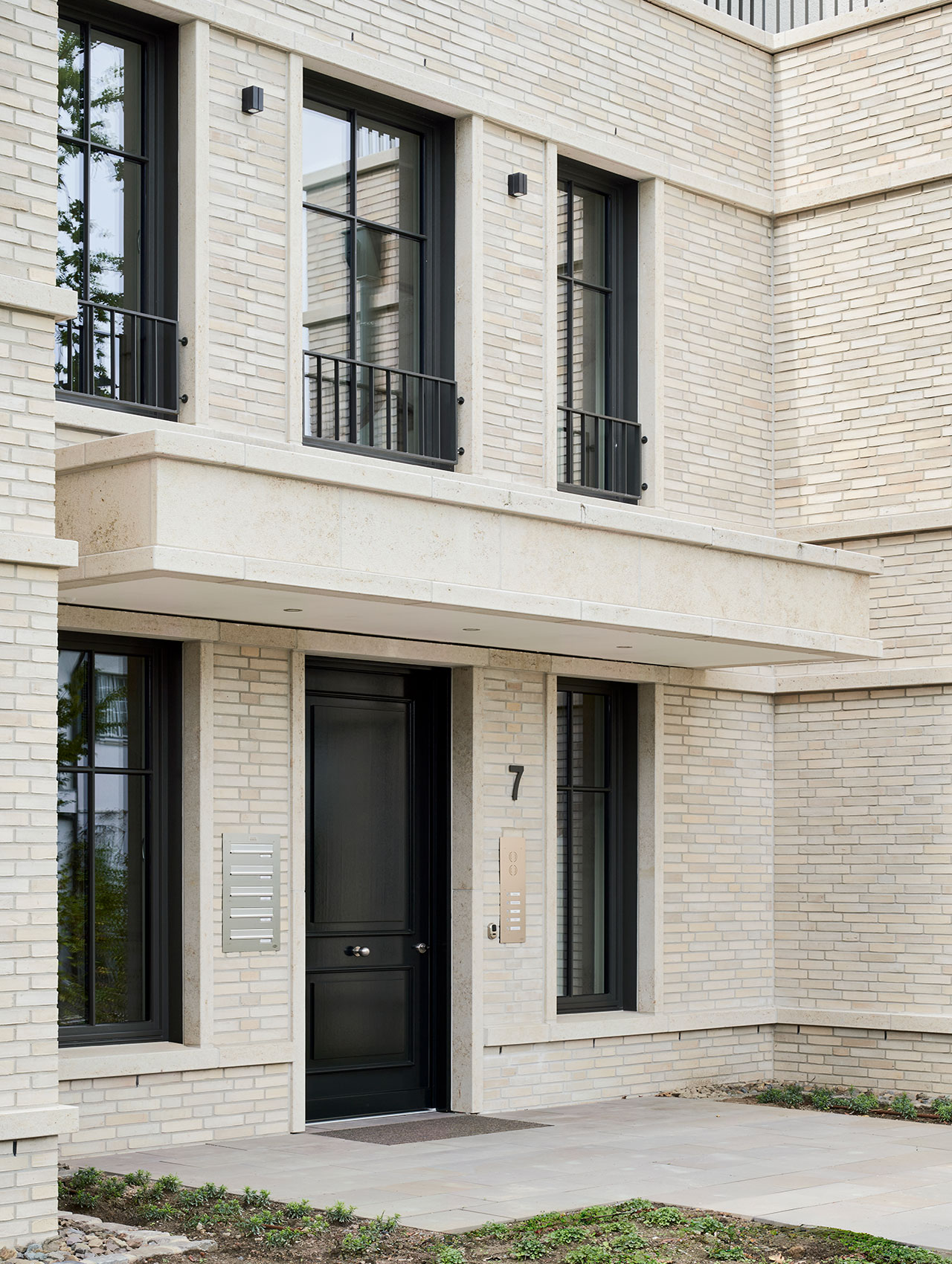 Eingangsbereich mit heller Klinkerfassade und dunkler Haustür