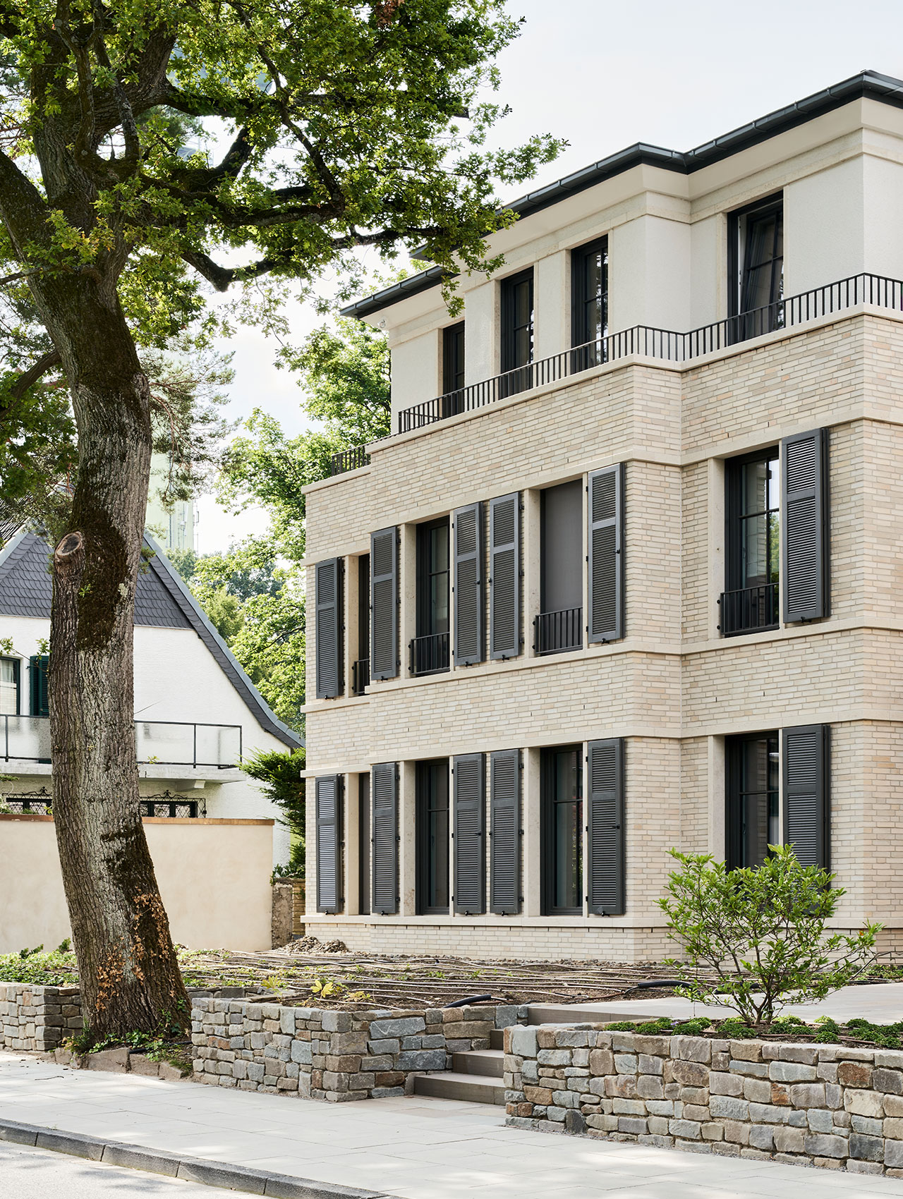 Fassadenansicht des Mehrfamilienhauses mit Baum im Vordergrund