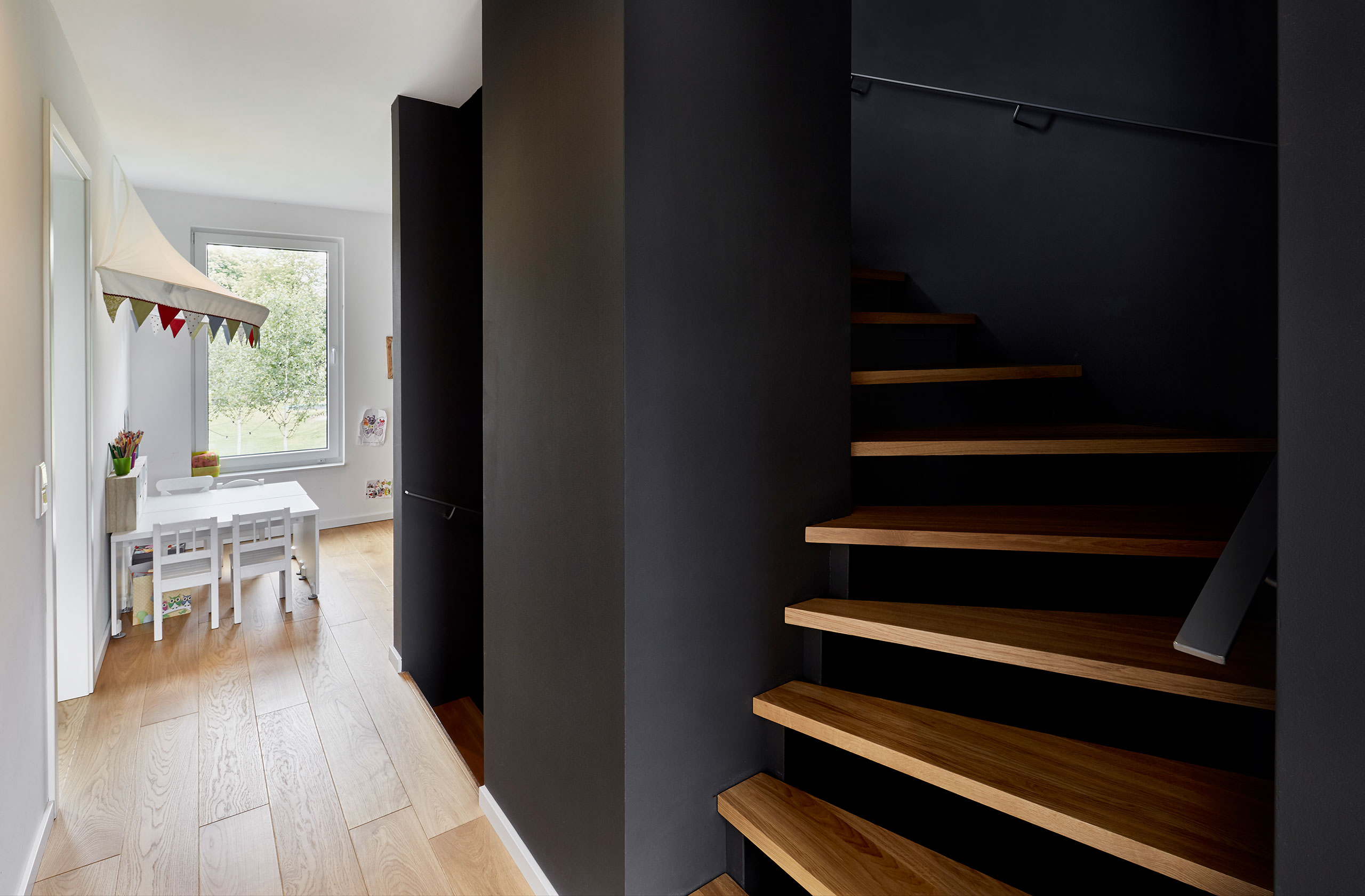 Treppenhaus mit dunkler Wandgestaltung und Holzstufen