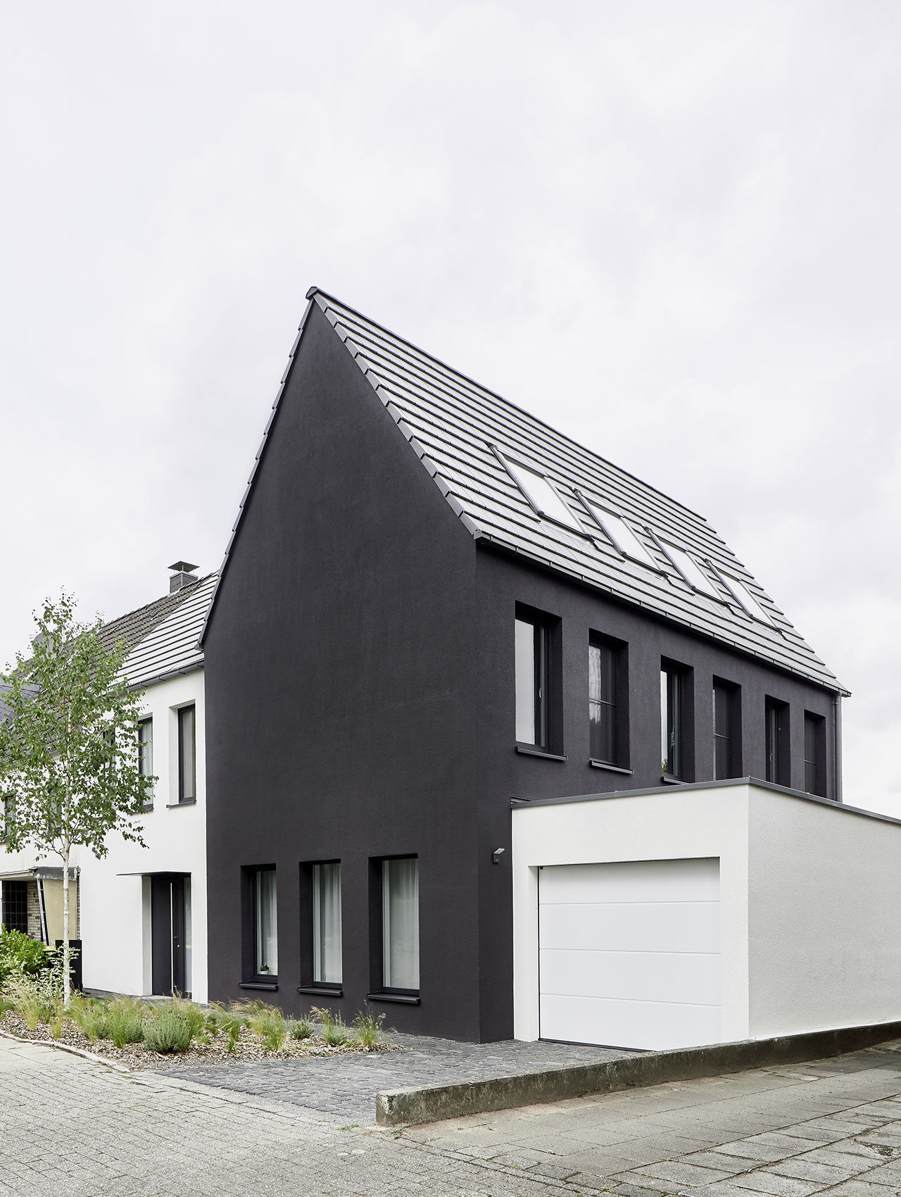 Straßenansicht des Einfamilienhauses mit dunkler Putzfassade