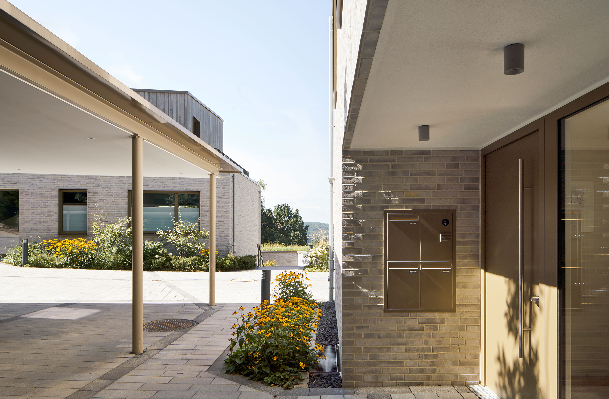 Eingangsbereich mit hellem Klinkermauerwerk, überdachtem Zugang und Bepflanzung