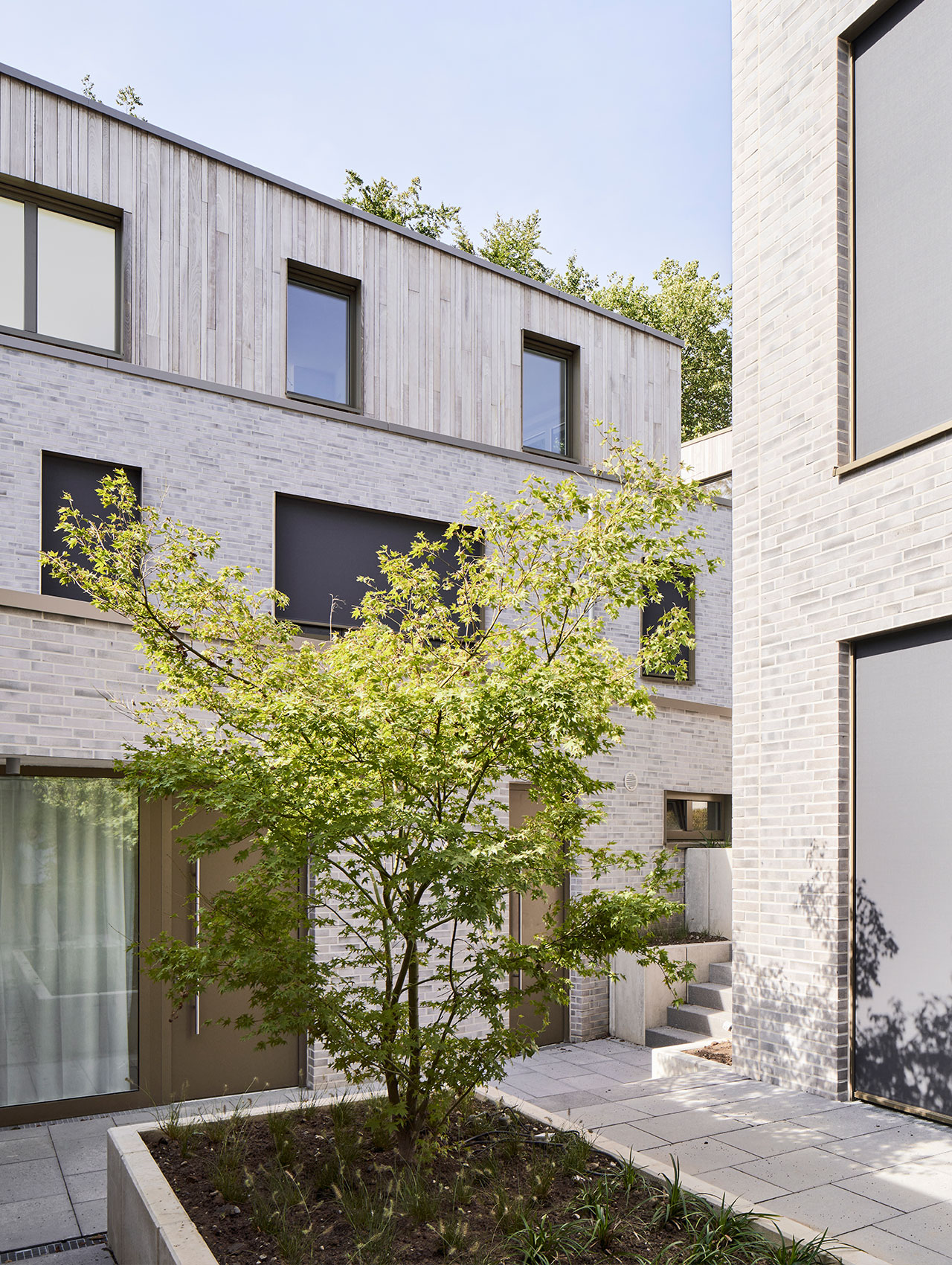 Innenhof des Wohnquartiers mit Baum und hellem Klinker