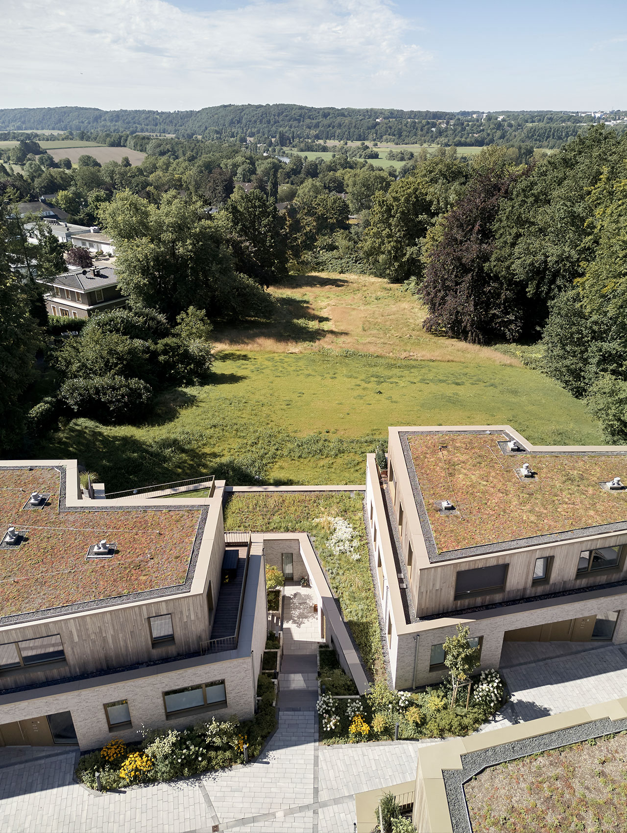 Blick von oben auf das Wohnquartier mit begrünten Dächern und Talblick